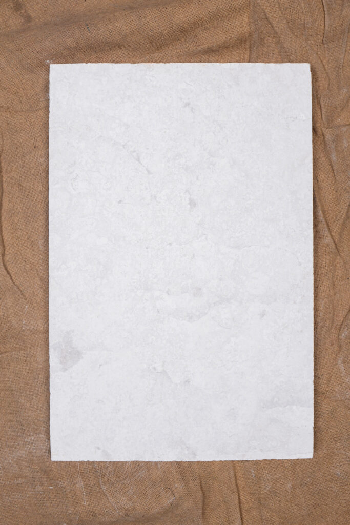 Polished white limestone slab photographed on timber planks
