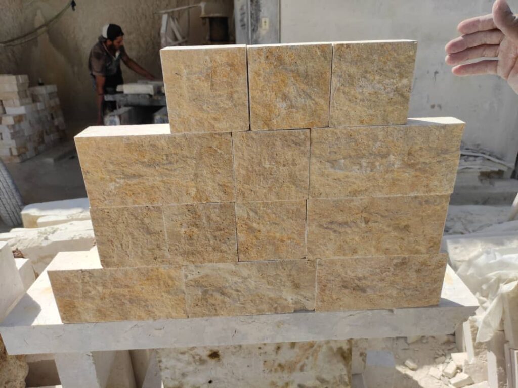 Gold-toned split-face wall blocks stacked in the workshop