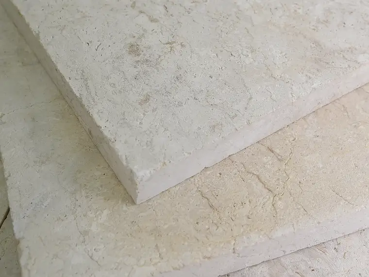 Large-format veined limestone slabs stacked at the stone facility