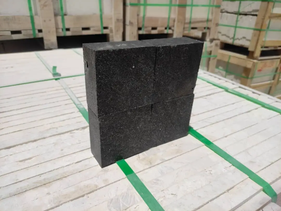 Dark Stone Blocks Stacked Dark cobblestone pavers stacked neatly on a pale surface with green straps