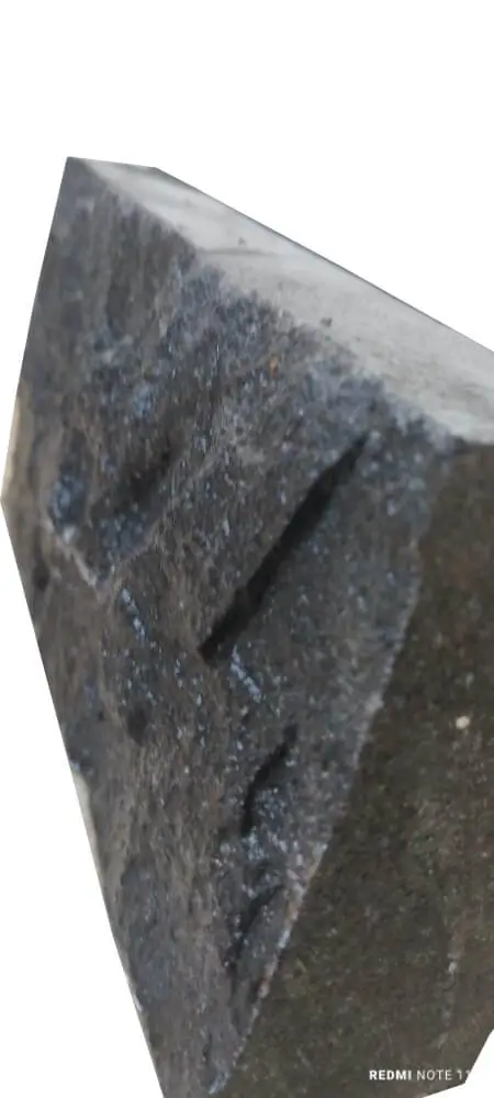 Close-up view of a dark, textured cobblestone block with etched markings, an example for cobblestone for driveway.