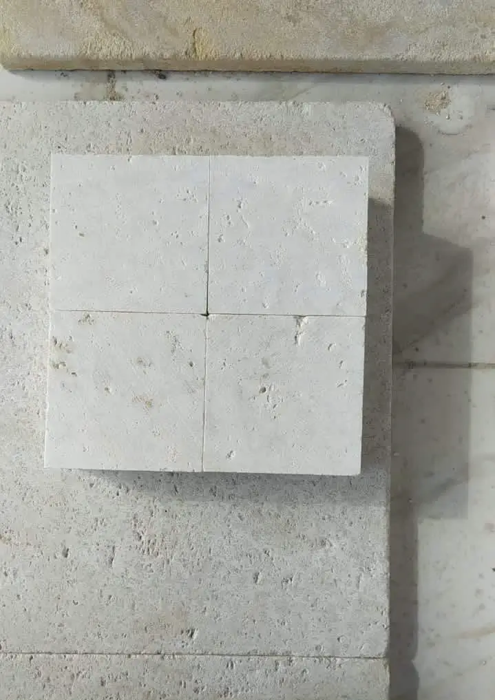 Close-up of four white cobblestone tiles with visible texture and grout lines, an example for cobblestone pavers for patio.