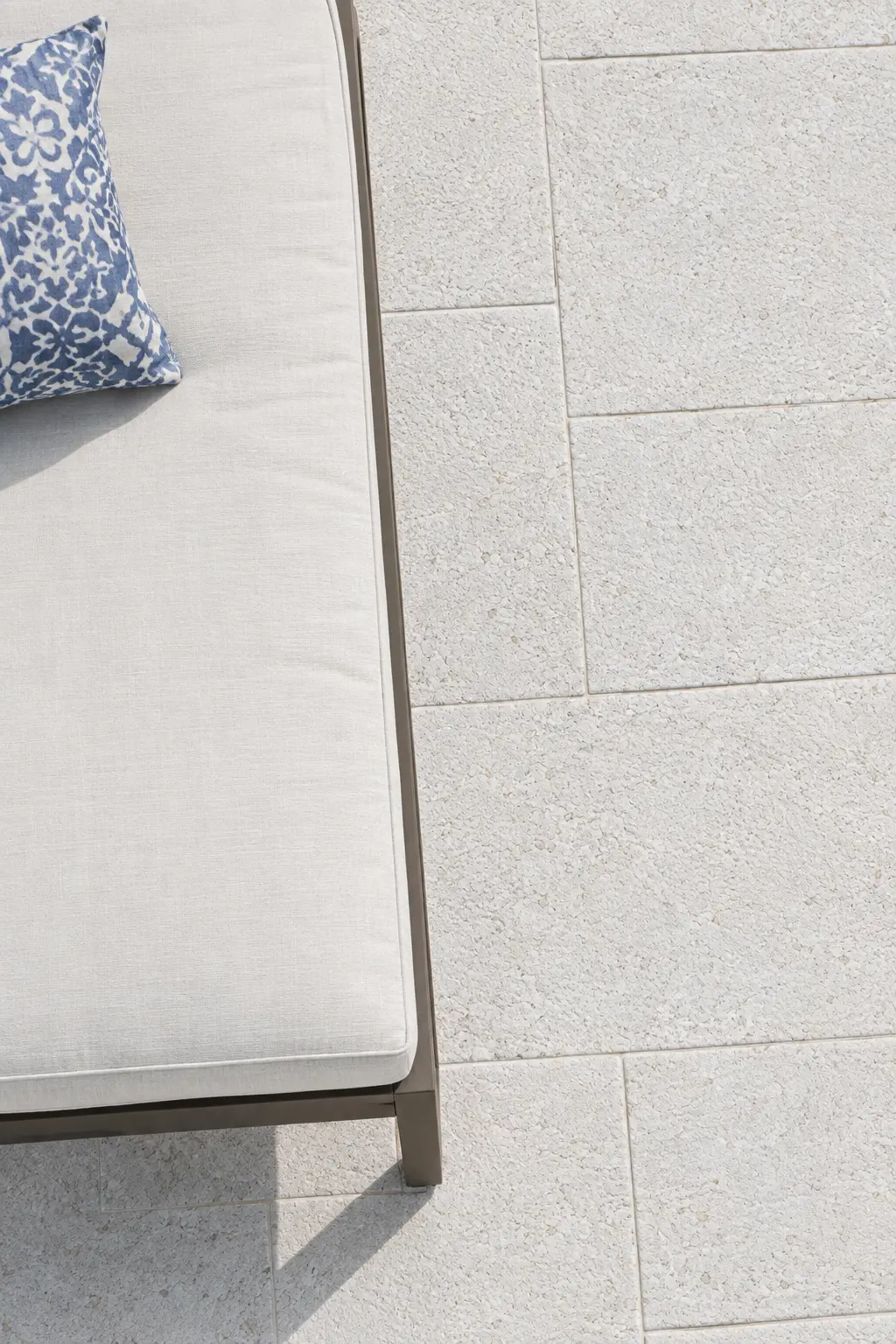 Close-up of light-colored textured travertine pavers with a subtle pattern detail.