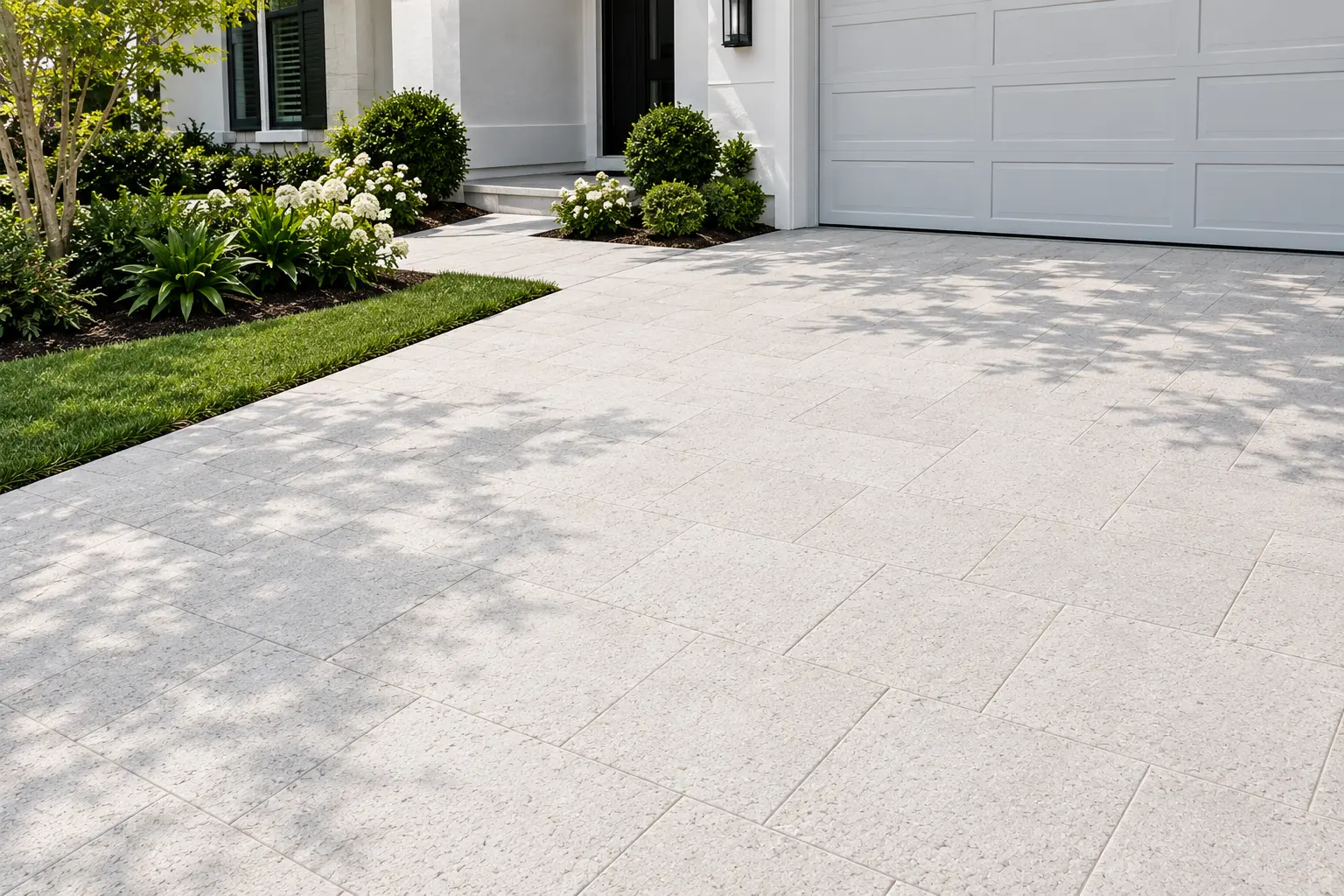 Light-colored marble pavers form a modern driveway with green lawn and manicured shrubs, a reference for snow white marble fading.