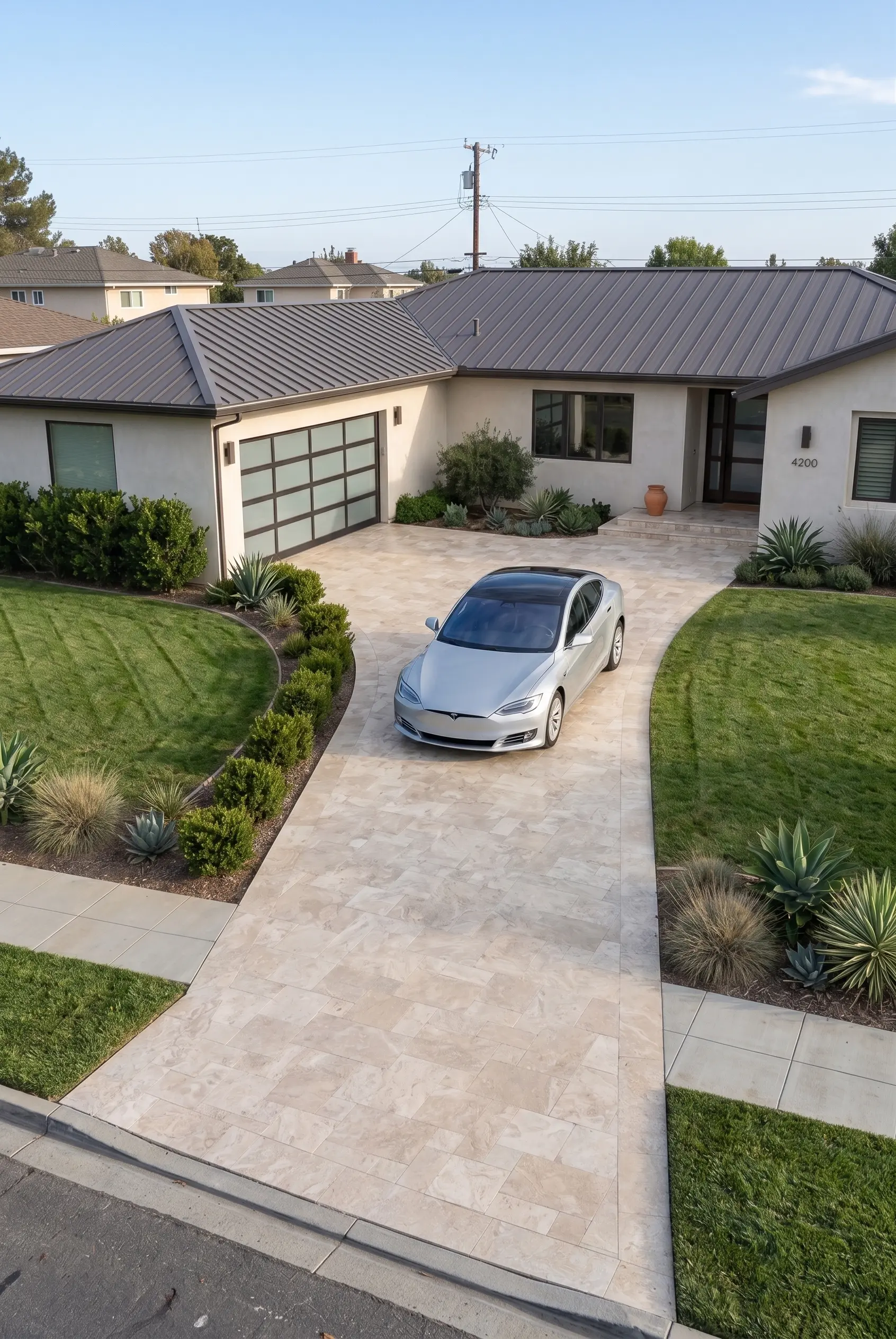 Silver Tesla parked on a natural stone tile driveway in front of a modern home, a reference for snow stone pavers.