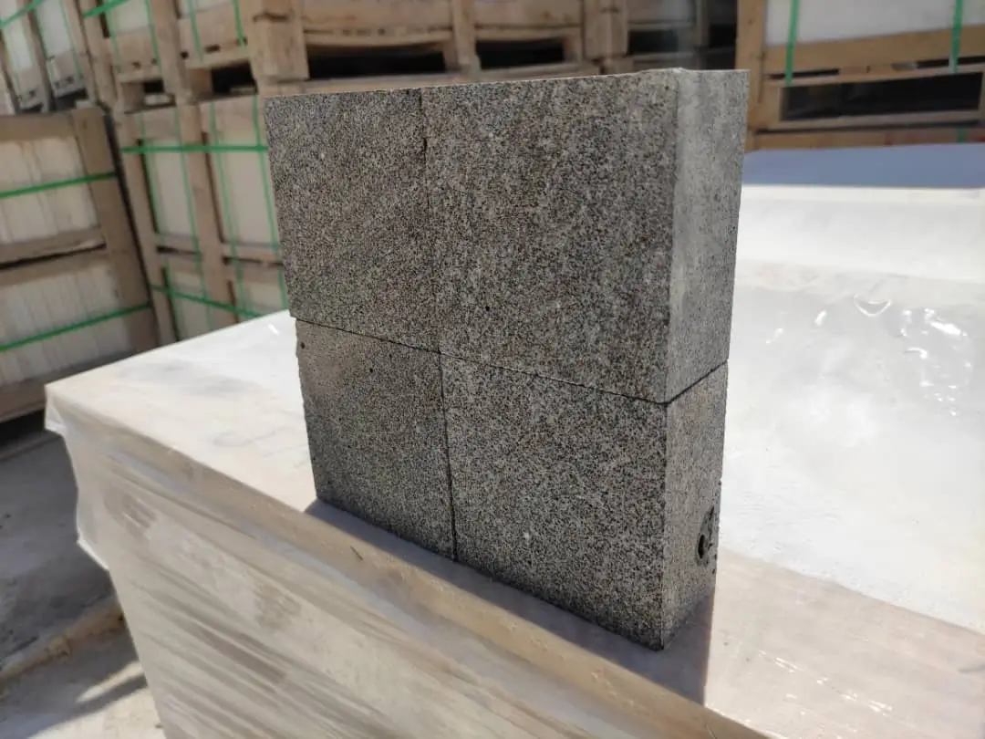 Stacked granite blocks with speckled texture displayed on a pallet for construction, shown for paver walkway ideas.