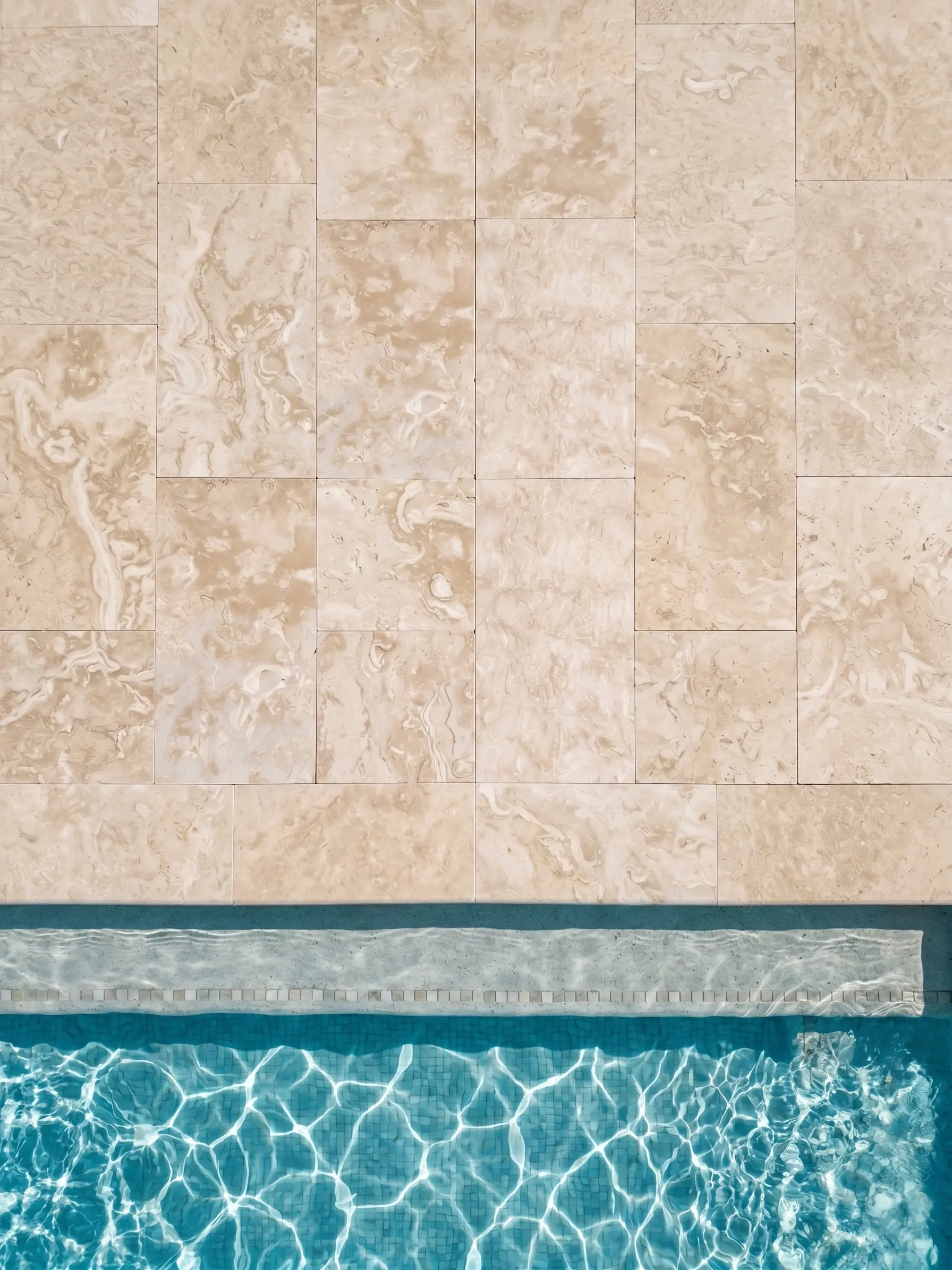 Travertine Tile and Pool Water Close-up of light-colored travertine pavers with a bright blue swimming pool edge