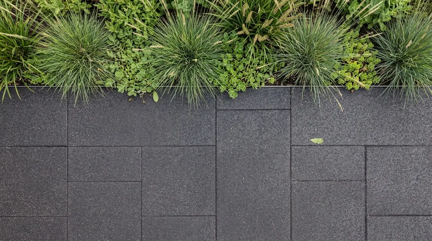 Honed black basalt finish pavers with a granular texture adjacent to lush greenery.