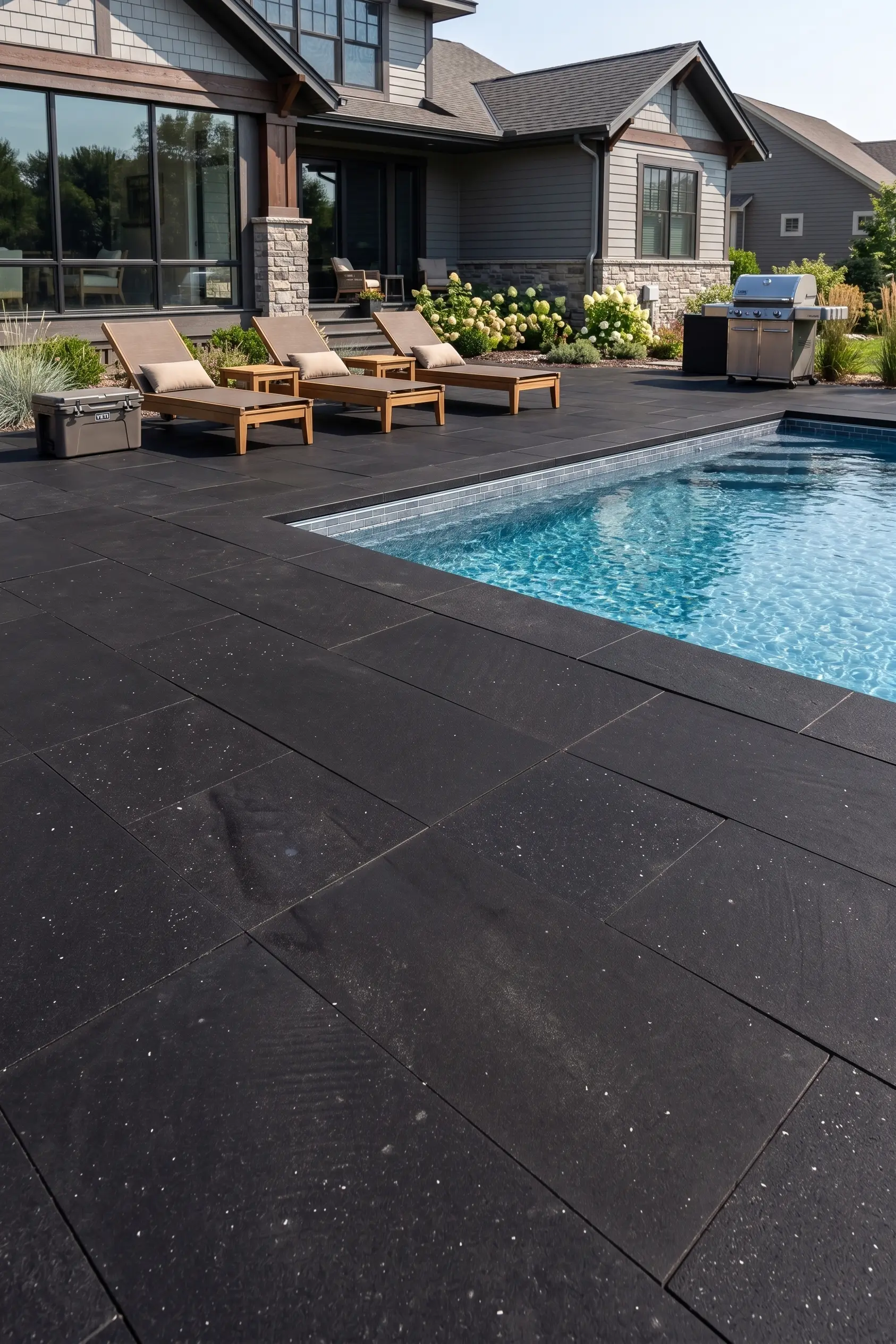 Dark Basalt Patio Beside Swimming Pool Dark basalt tiles form a patio around a swimming pool.