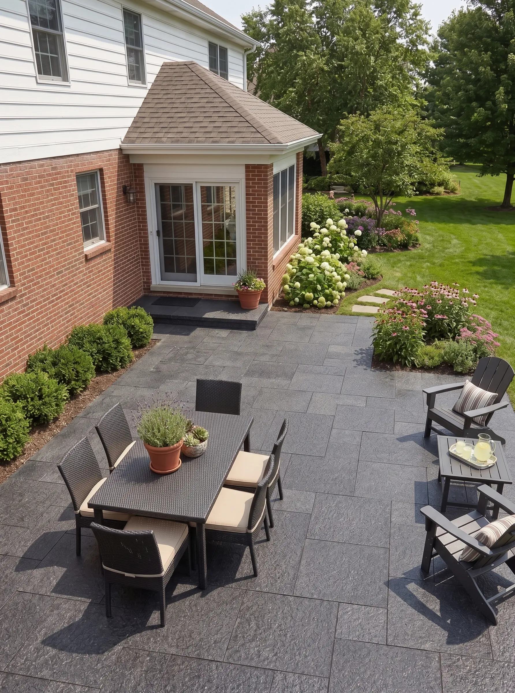 Dark Stone Patio with Dining Set Dark stone patio paving with a woven dining set and chairs.
