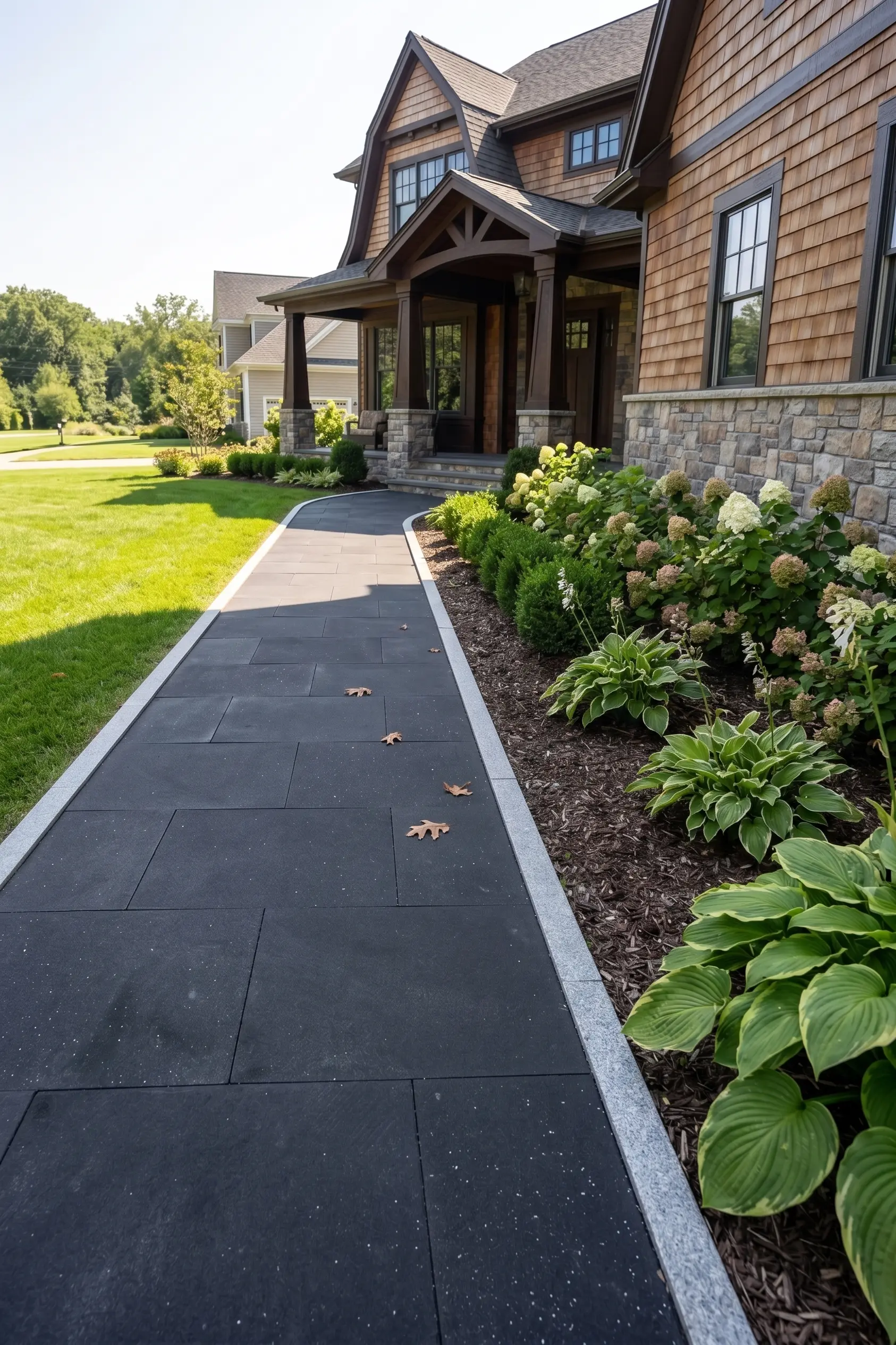 Dark large format pavers next to landscaping Dark large format basalt pavers with basalt edging and garden beds