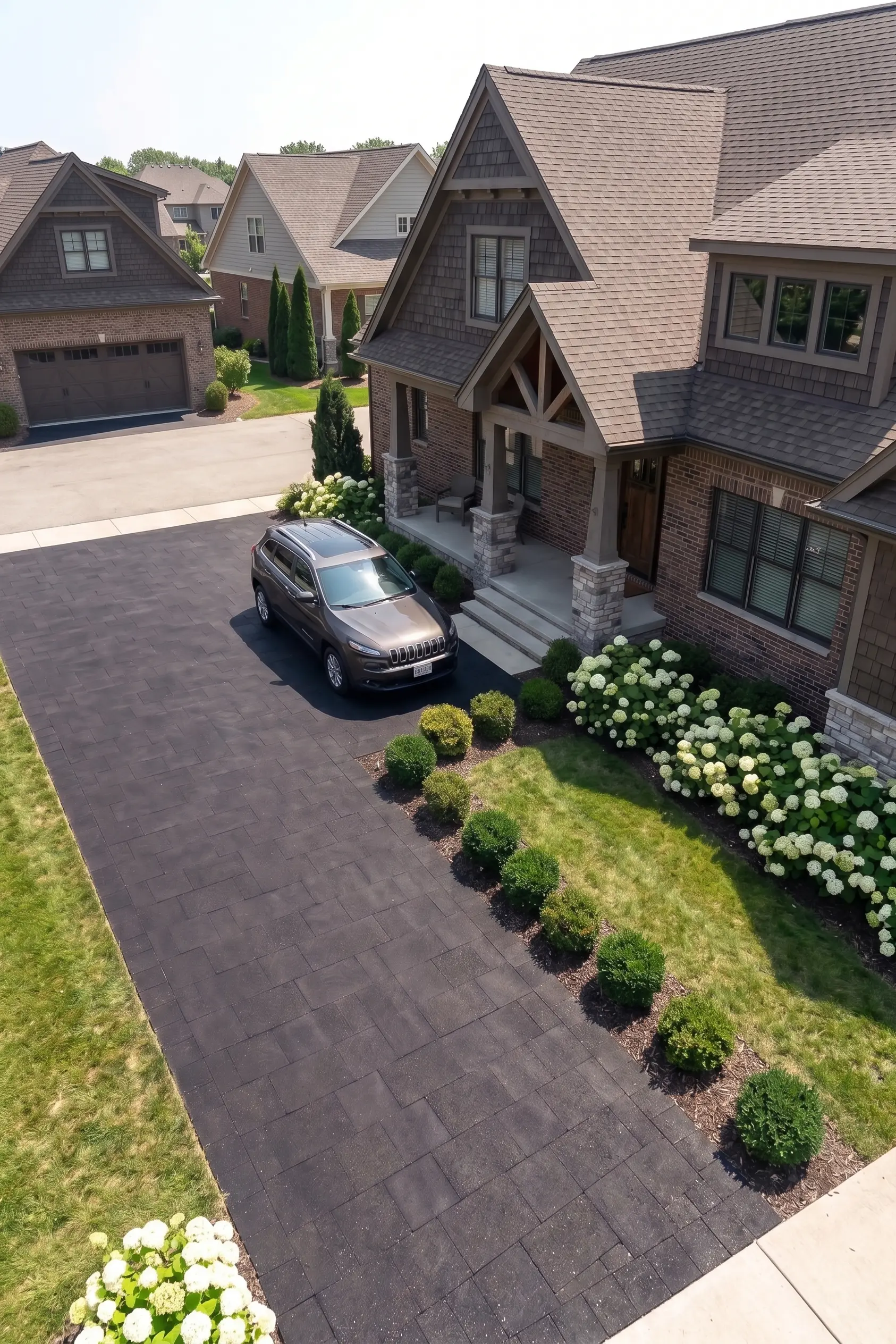 Dark rectangular pavers on a driveway next to green lawn and landscaping.