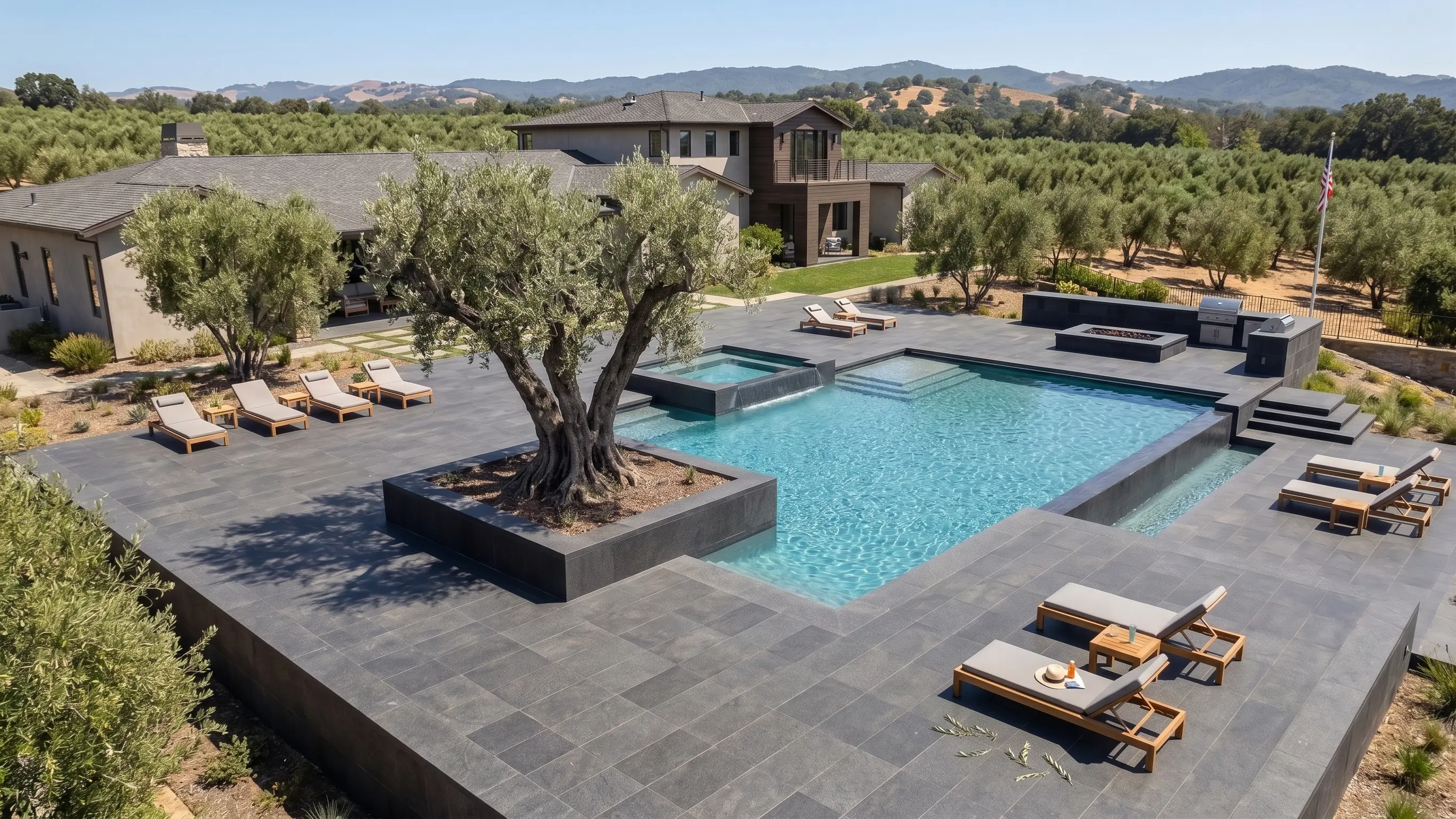 Gray stone pavers surround a modern pool with lounge chairs.