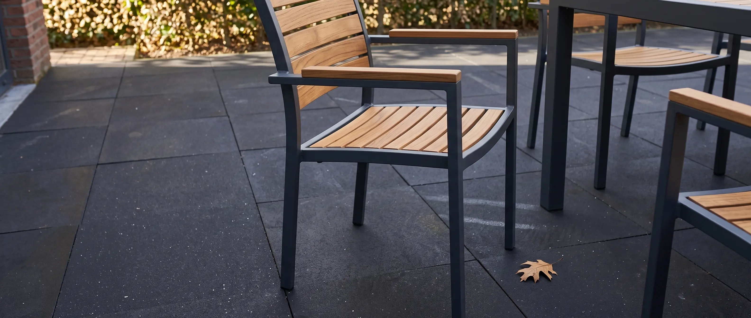 Outdoor chair on dark paving Modern outdoor chair with wooden slats on a dark basalt crazy paving patio surface.