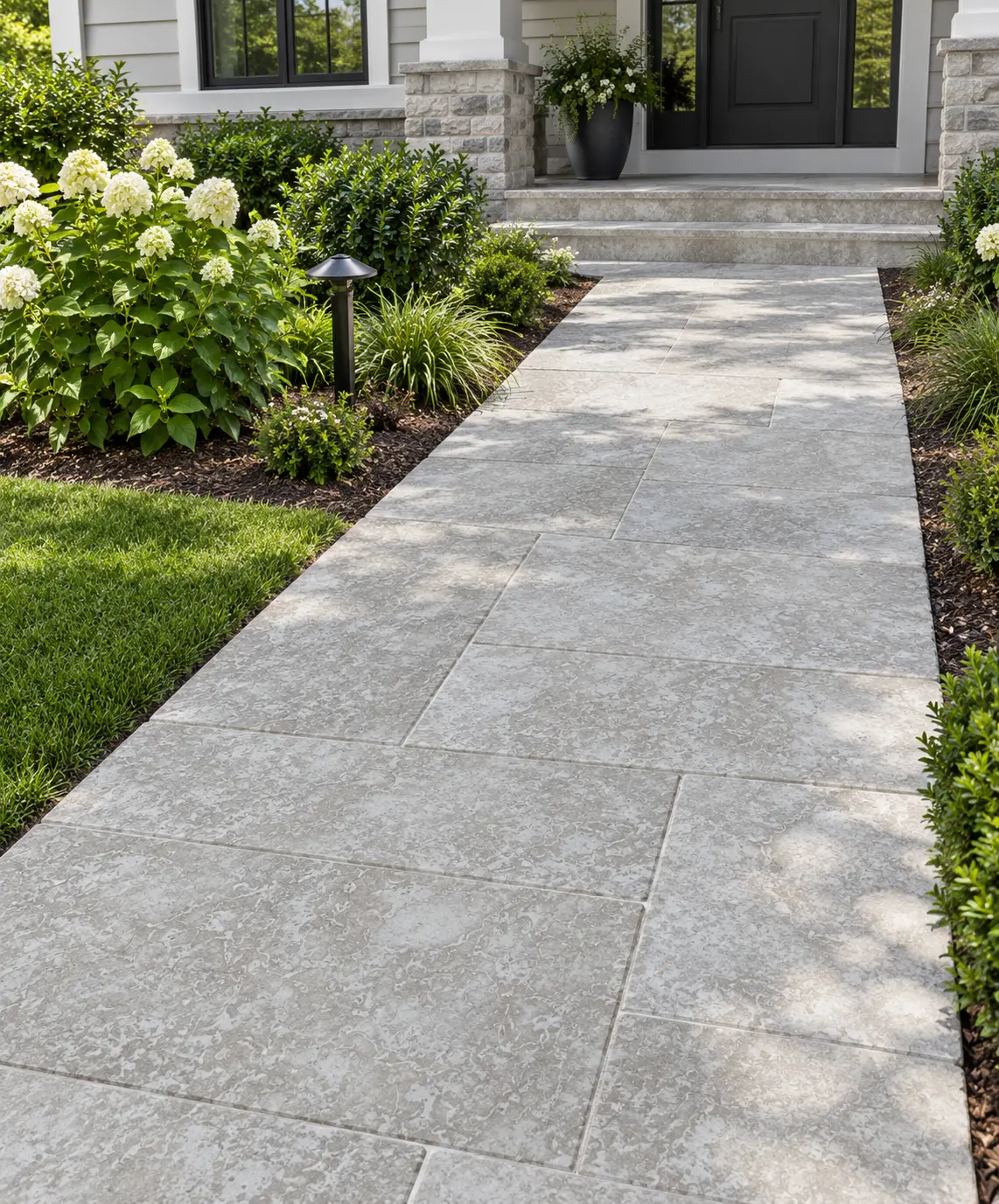 Natural stone pavers form a clean pathway leading to a home's entrance, pictured for install marble pavers.