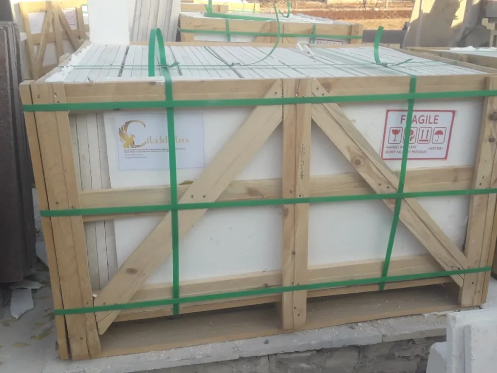 Wooden crate with diagonal bracing, green straps, a Citadel Stone label and a fragile label.