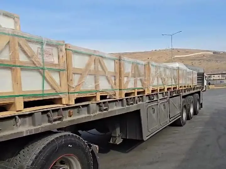 Flatbed trailer loaded with braced wooden crates at a port.