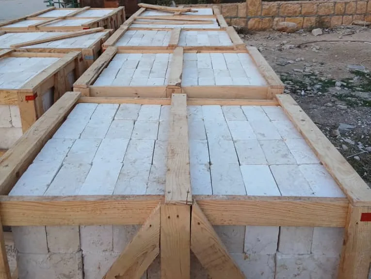 Wooden crates filled to the top with white tumbled stone, with braced sides.