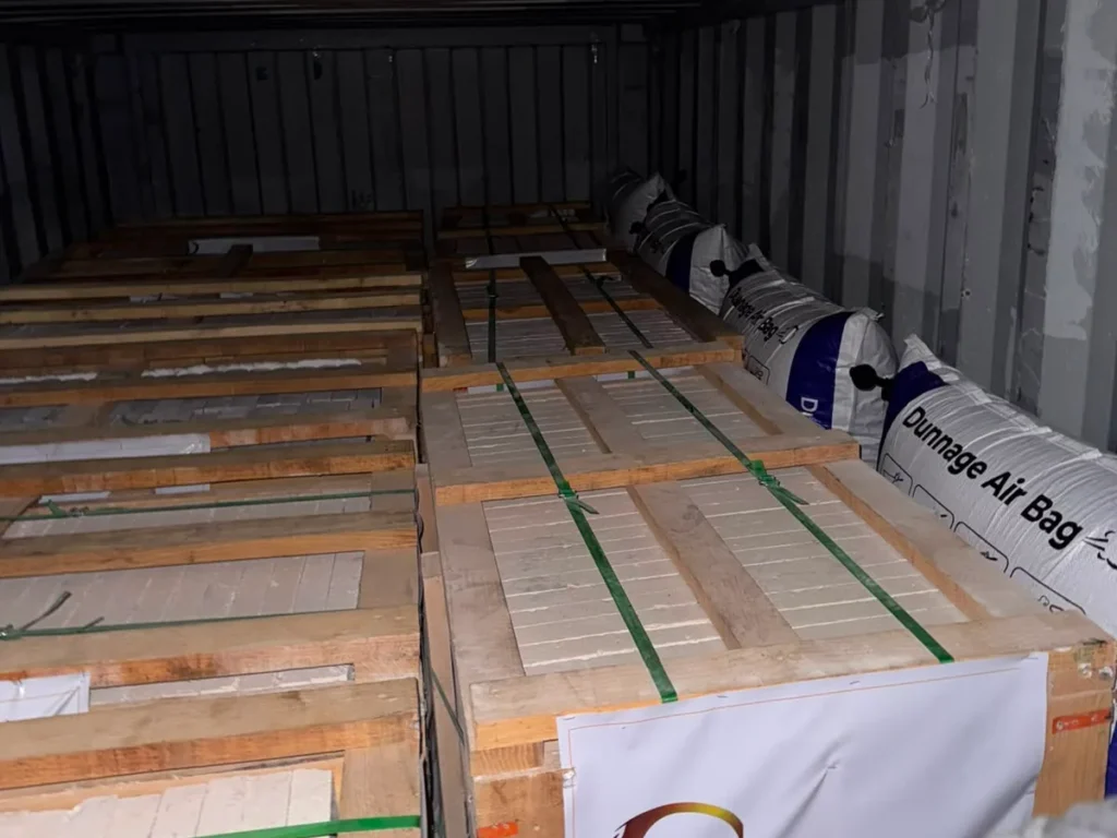 Inside a container: rows of stone crates, with inflatable dunnage bags between them and the wall.