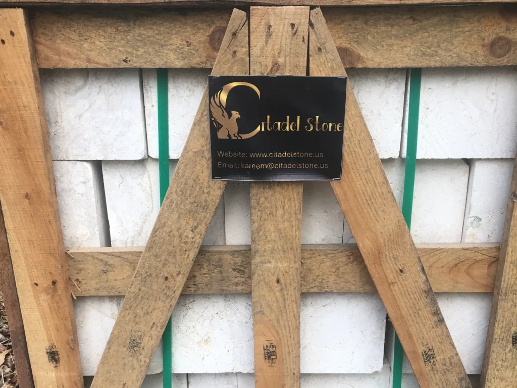 Front of a braced wooden crate of white stone with a black Citadel Stone label.