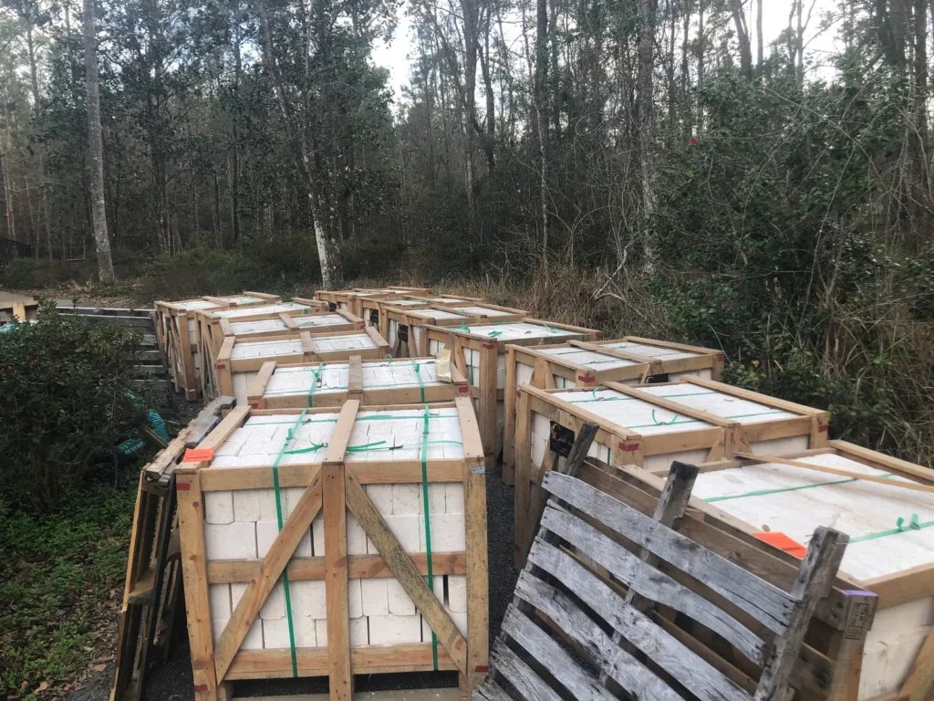 Wooden crates of white stone standing on a wooded site.