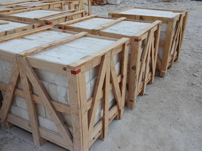 Row of wooden crates filled with white stone, braced with diagonal timbers.
