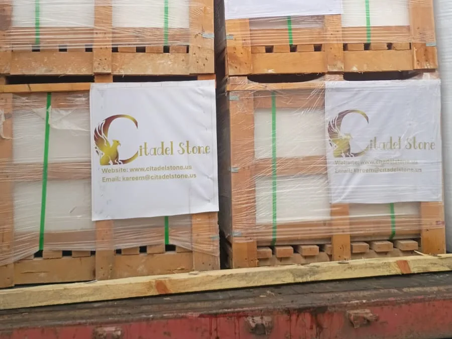 Open container on arrival, its red sill in view, with film-wrapped wooden crates of stone stacked two high and Citadel Stone labels on the lower crates.