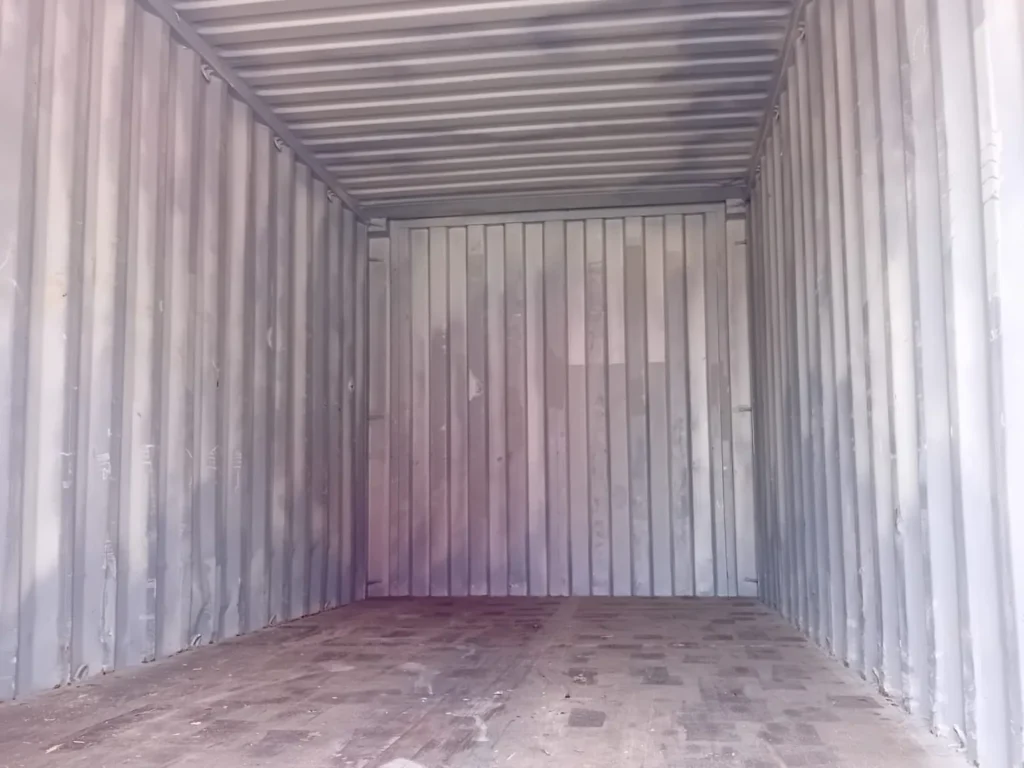 Empty shipping container with grey walls and a wooden floor.