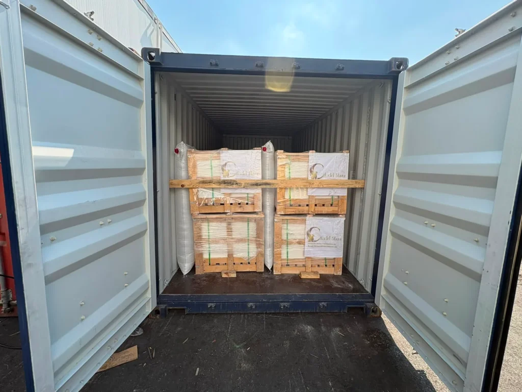 Container with both doors open, showing crates of stone stacked two high with a timber bar across them and white air bags between the stacks.