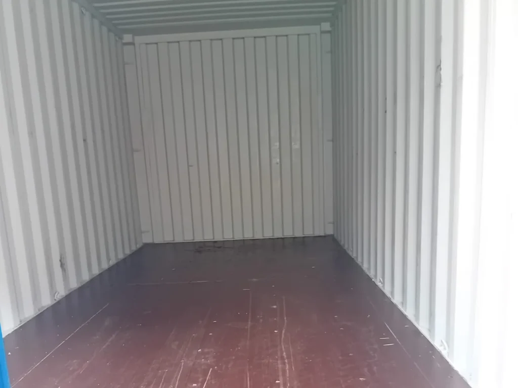 Empty shipping container with white walls and a dark wooden floor.