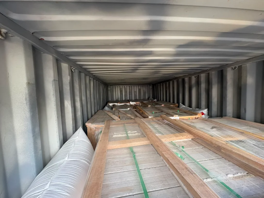 View down the length of a container over the tops of film-wrapped crates, with a white air bag along one side.
