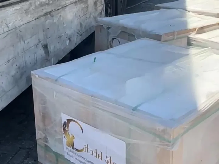Film-wrapped crate with a Citadel Stone label beside a truck at the port.