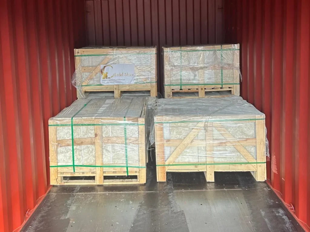 Crates of stone stacked two high inside a red-walled container.